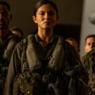 Jay Ellis, Monica Barbaro, and Danny Ramirez stand lined up in a hangar