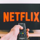 A remote control pointing at a TV screen with a Netflix logo