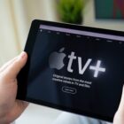 A person holding an iPad with Apple TV+ on the screen.