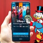 Scrooge McDuck over an image of someone holding a phone with Disney+ on the screen