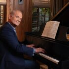 Kelsey Grammer as Frasier Crane sitting behind a piano in the Frasier reboot