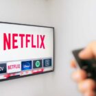 A Person holds an Apple TV remote using the new Netflix app with a hand. Netflix dominates Golden Globe Nominations. Illustrative