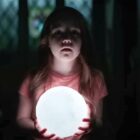 A girl holds a light in a dark room