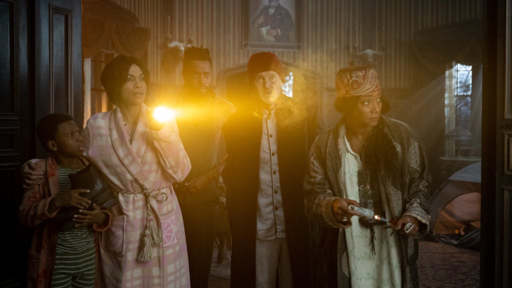Chase Dillon as Travis, Rosario Dawson as Gabbie, LaKeith Stanfield as Ben, Owen Wilson as Father Kent, and Tiffany Haddish as Harriet investigating together in Haunted Mansion