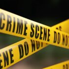 Yellow crime scene do not cross barrier tape in front of defocused background.