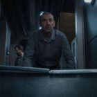 A man in gray work coveralls embellished with a 