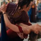 Prince Yan dips Carol Danvers as they dance. Carol is wearing a red dress with her iconic gold star on the chest.