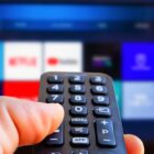 A TV remote in front of a blurred screen with streaming apps