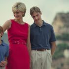 woman in red dress stands outside with her young sons