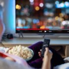 Woman relaxing at home in evening and watching TV