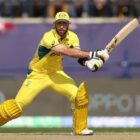 Glenn Maxwell of Australia, wearing bright yellow kit, swings his bat at the crease ahead of the India vs Australia live stream for the Cricket World Cup final 2023.