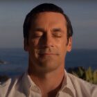 Jon Hamm sits in nature with a smile in Mad Men.