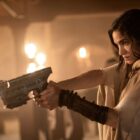 Kora points a pistol at someone off-camera in Netflix