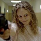 Heather Graham holding a gun and looking frantic in the movie Suitable Flesh