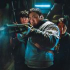 A still from Badland Hunters, Don Less is aiming a gun past the camera, with two young companions behind him