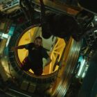 a man floats in zero gravity inside a cramped spacecraft while looking at a giant spider