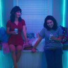 Two young women holding beers in a room with neon lights in this image from Animal Pictures.