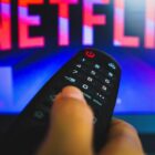 person holding remote in front of tv screen with netflix logo