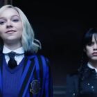 Enid (Emma Myer) and Wednesday (Jenna Ortega) standing in a doorway