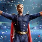 A white male superhero stands with his arms spread as confetti rains down in 