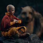 young boy meditates while sitting on a rock