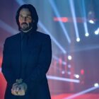 Keanu Reeves as John Wick, with spotlights behind him, in John Wick: Chapter 4