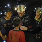 A group of divers stand around a small boy in the movie Thirteen Lives