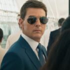 Tom Cruise stands in a crowd wearing sunglasses in Mission: Impossible - Dead Reckoning Part One.