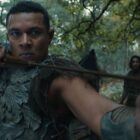 A close up of Arondir with his bow primed for action as Isildur stands in the background in The Rings of Power season 2