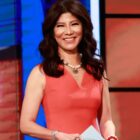 Julie Chen Moonves standing on the set of Big Brother, holding a cue card.