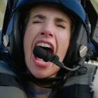 a woman in a fighter pilot helmet screams inside a cockpit