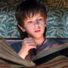 Jared Grace reading an old book in bed while holding a torch in The Spiderwick Chronicles.