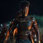 General Nanisca stands stoically at night in The Woman King