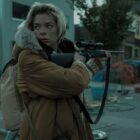 Rose pointing a gun and looking cautiously over her shoulder.