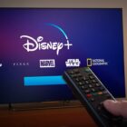 Image of Disney Plus being watched on a TV with a hand holding a remote control