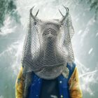 A person stands with antlers on their head covered by netting