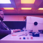 Dylan George sitting at his computer terminal in Severance Season 2