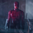 Daredevil as seen through a window with a red light shining on him in Daredevil: Born Again episode 9