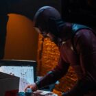 masked daredevil looks at papers on a table in marvel's daredevil's born again