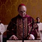 Ralph Fiennes in Conclave about to give a speech at a lecturn