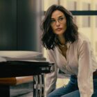Cami kneels on the floor of Monty's office