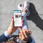Seated person using a social media app on a smartphone.