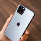 A hand holding an iPhone showing the Apple logo.