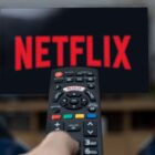 The Netflix logo on a TV, with a remote control pointed towards it