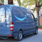 An Amazon Prime van parked on a street in front of palm trees.