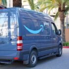 Blue Amazon Prime van parked near a building with palm trees.