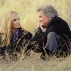 Michelle Pfeiffer and Kurt Russell sit in the middle of a grassy field