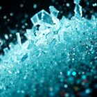 An abstract close-up photograph of shattered glass and glittering sequins, captured in dramatic, high-contrast studio lighting to create a sense of luxury and performative glamour.