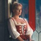 Margot Robbie's Catherine sitting on a window seat at night in 2026's Wuthering Heights movie
