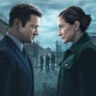A man and a woman look at each other outside prison gates